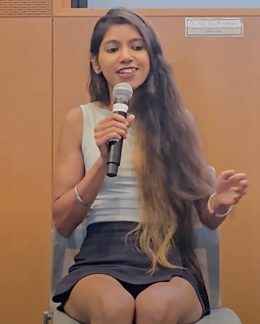 Ishween Kaur speaking with a microphone during a fireside session